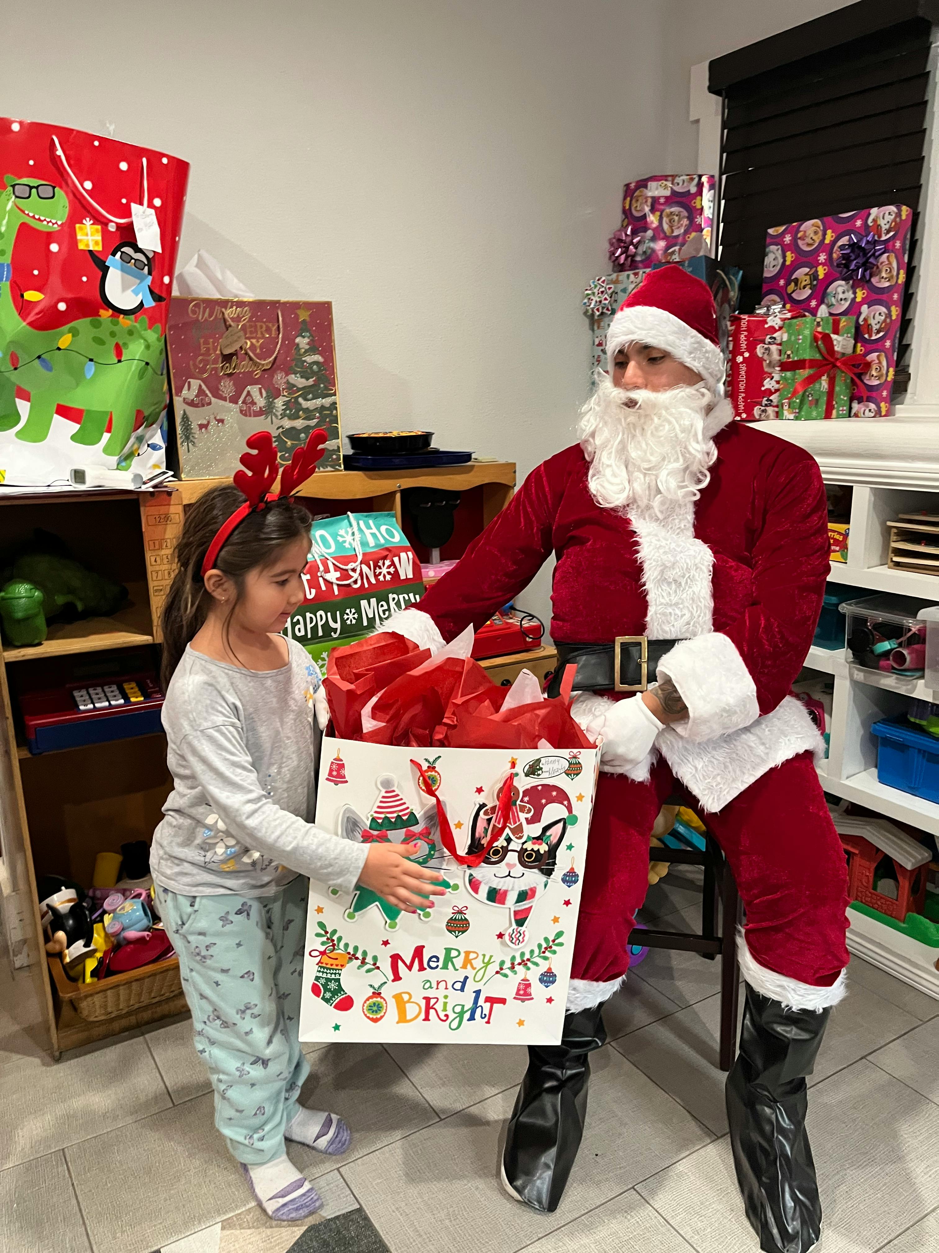 Person dressed as Santa Claus giving a gift bag to a child