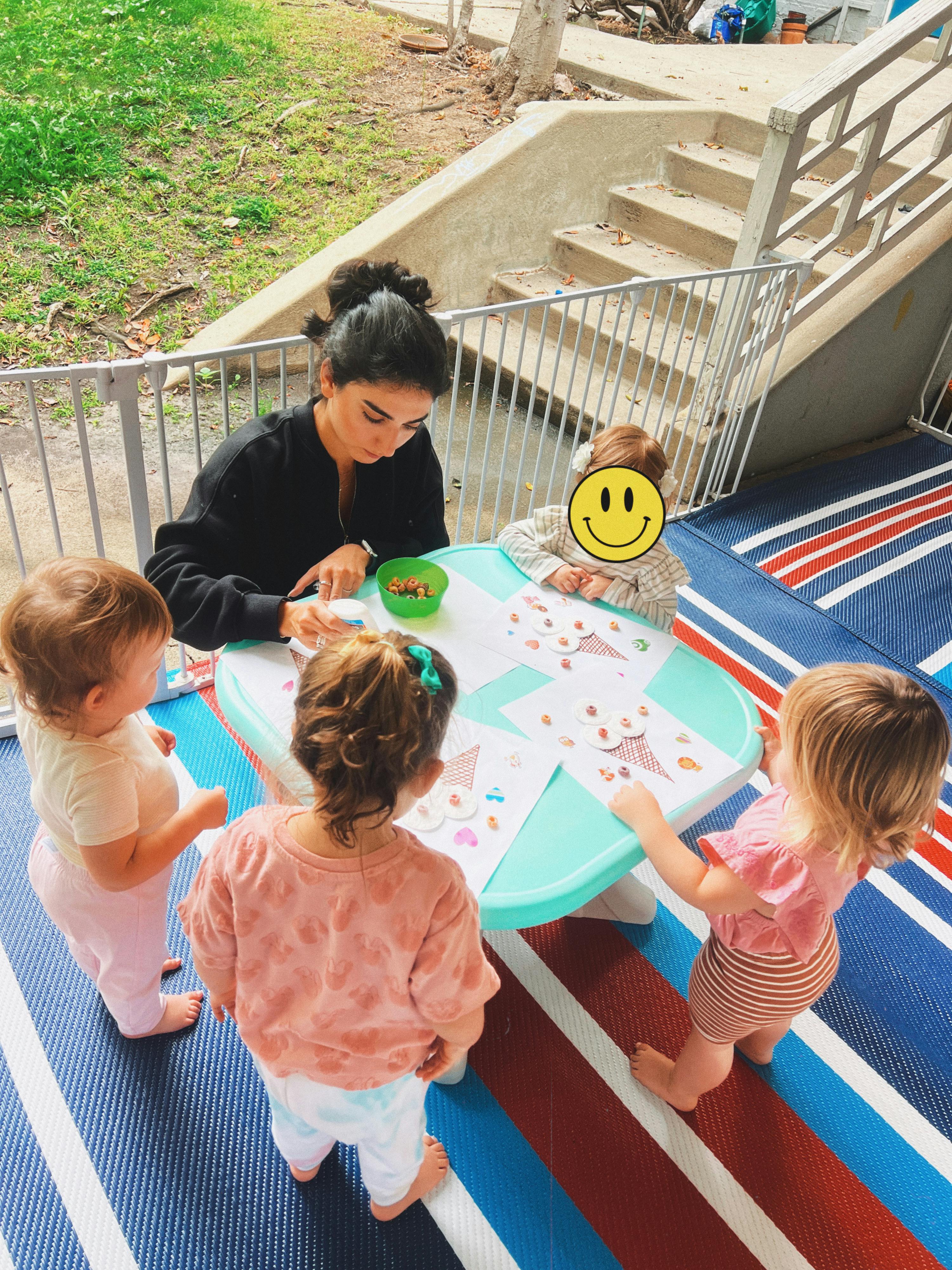 Adult and children crafting with cereal at a small table