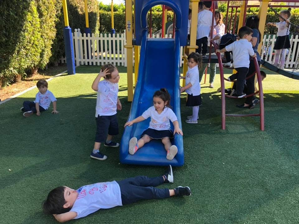 Children playing on a playground slide and climbing structure