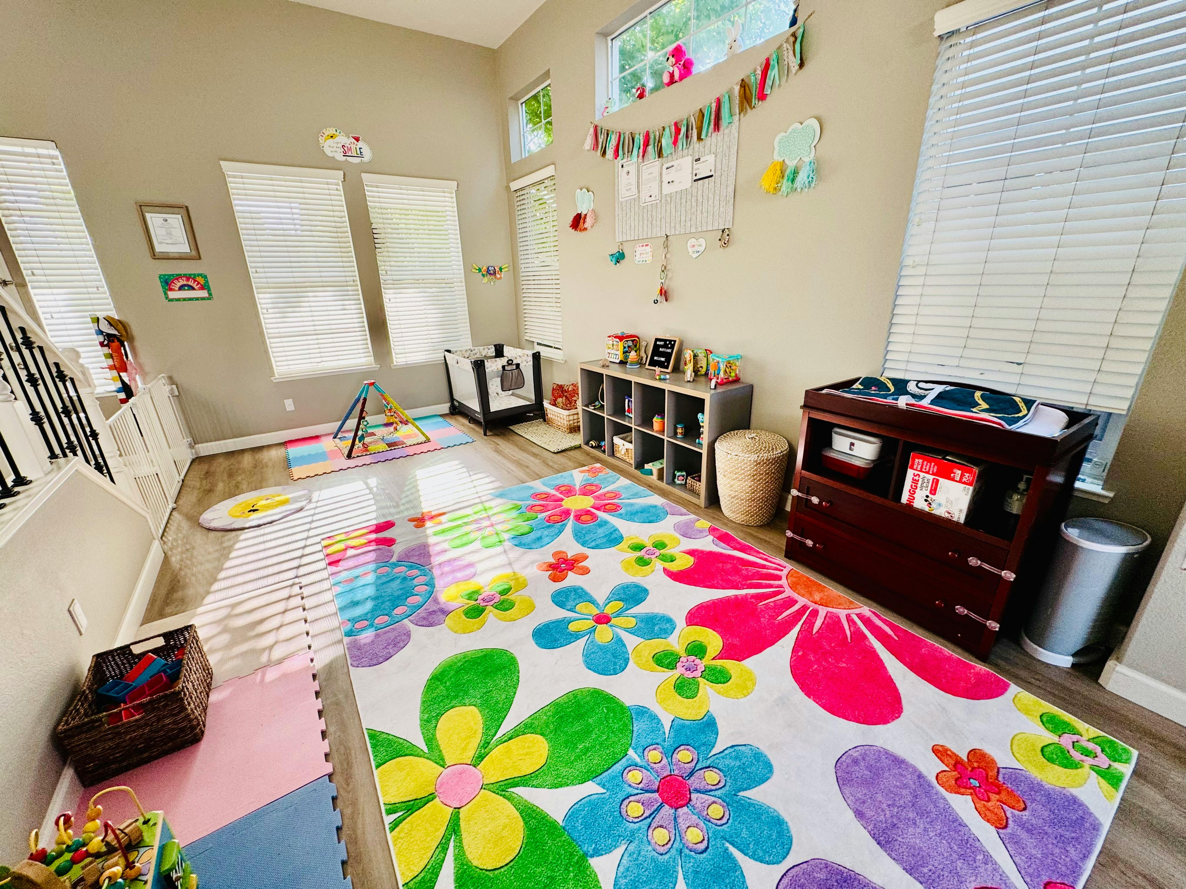 Playroom with a colorful floral rug, changing table, and toy storage