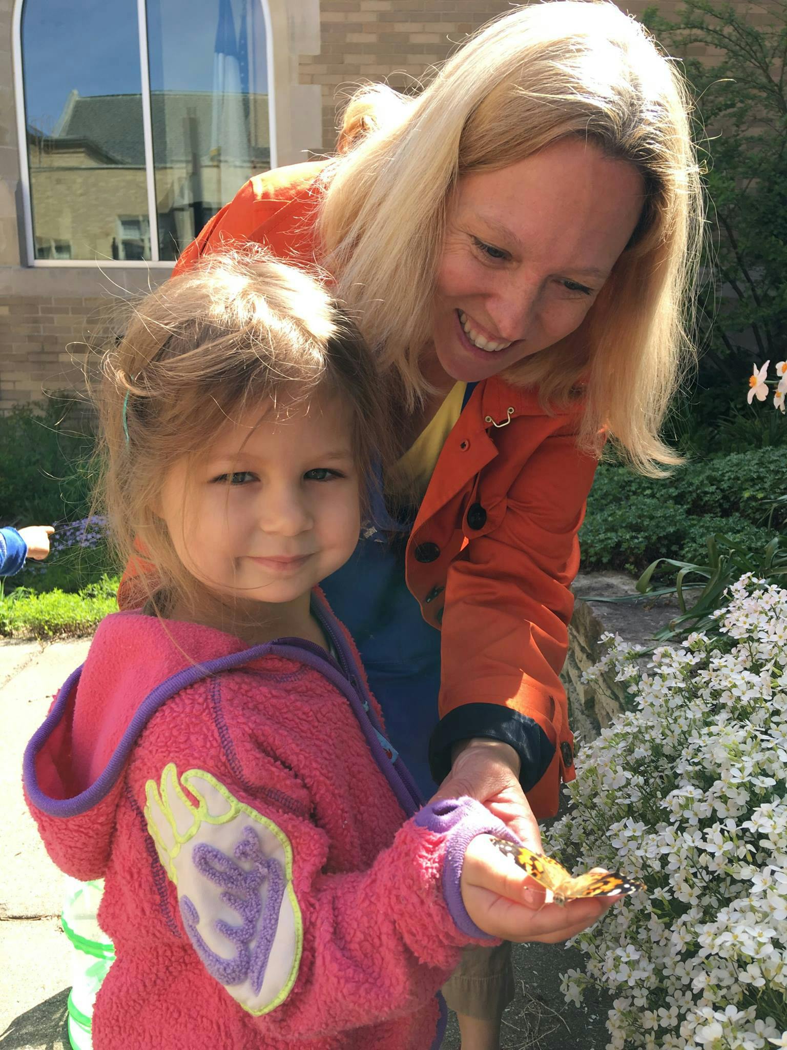 Adult and child looking at a butterfly on the child's hand