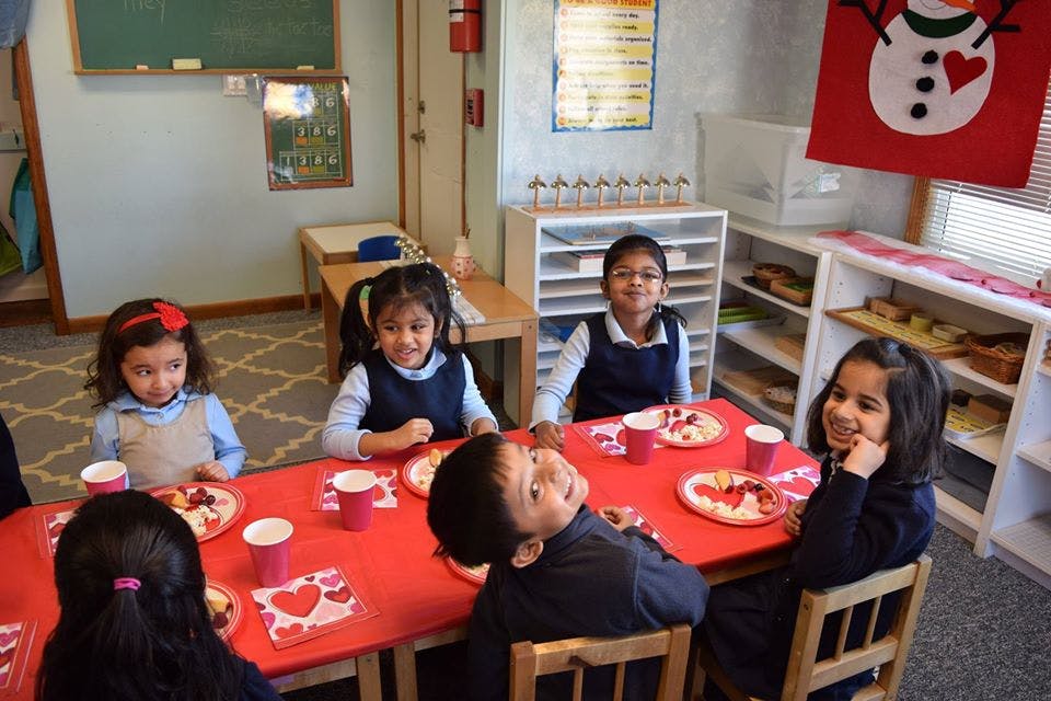 Children sitting at a table with red placemats and cups