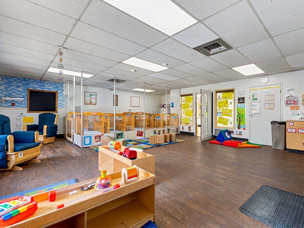 Classroom for children with cribs, play area, and rocking chairs