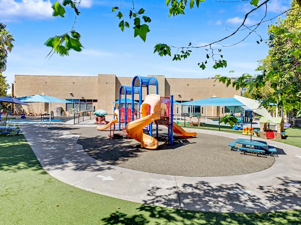 Empty children's playground with slides, swings, and blue shade structures