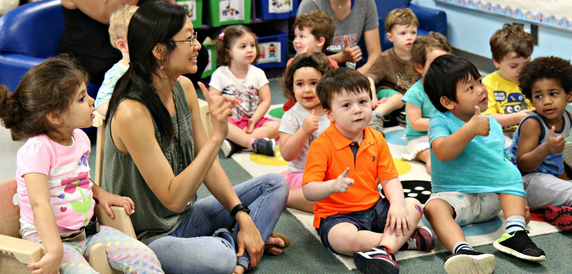 Person and children sitting on floor in a classroom