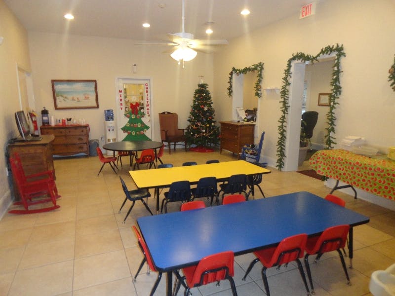 Room with multiple tables and chairs, decorated with Christmas garland and a tree