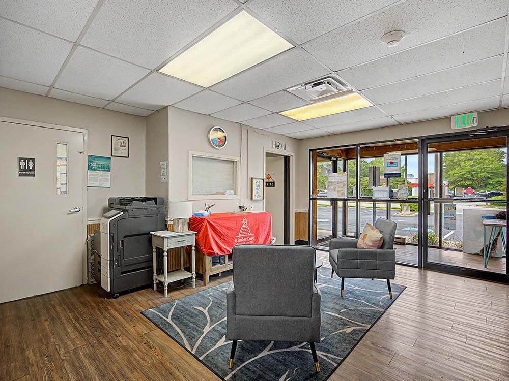 Lobby area with two armchairs, a large rug, and glass doors looking outside
