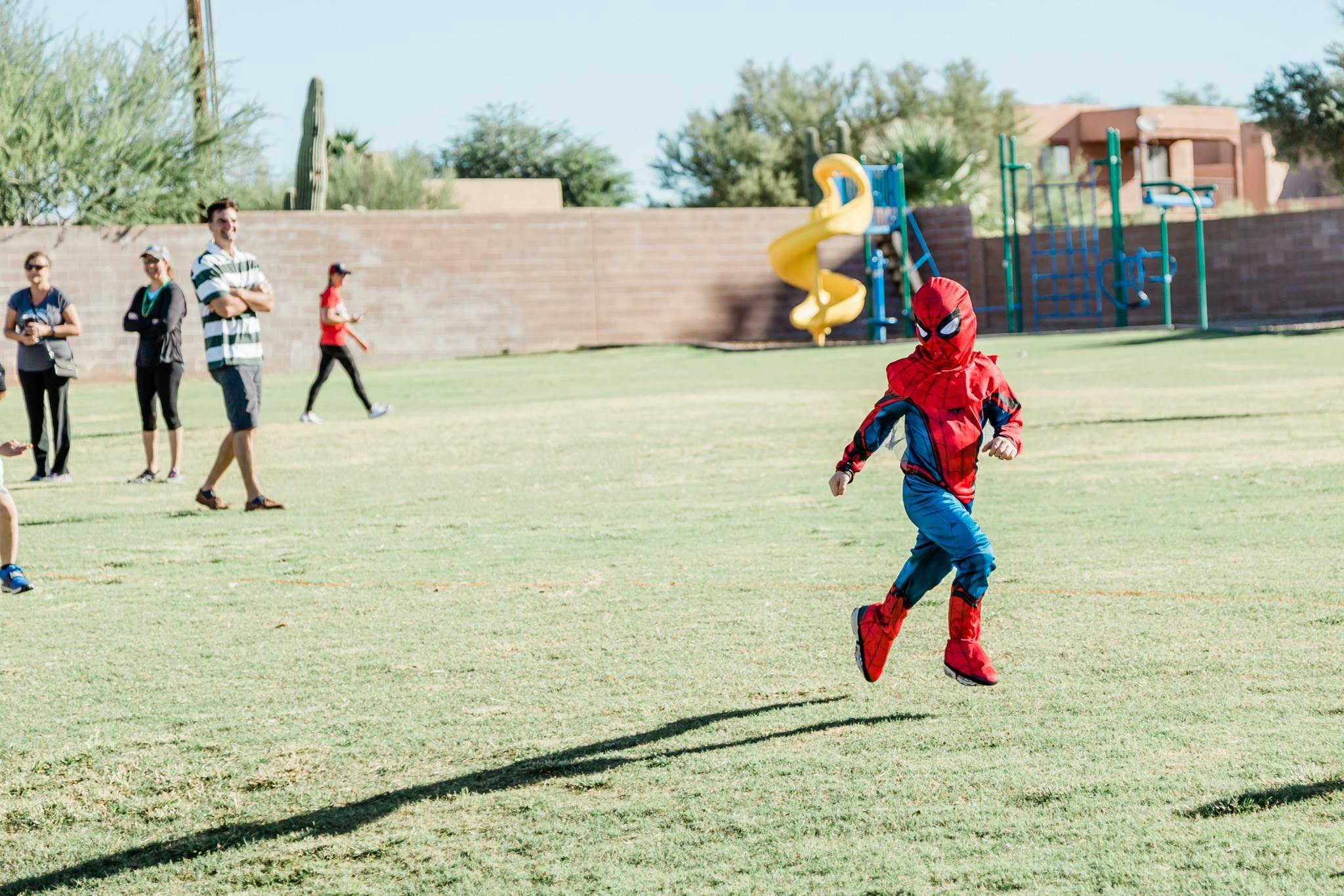 Child in Spider-Man costume running on grass