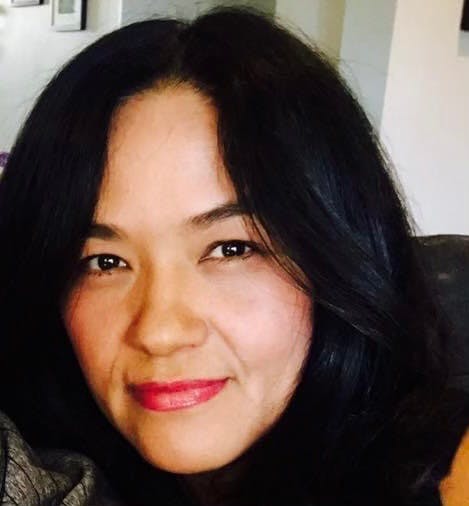 Close-up portrait of a person with dark hair looking at the camera