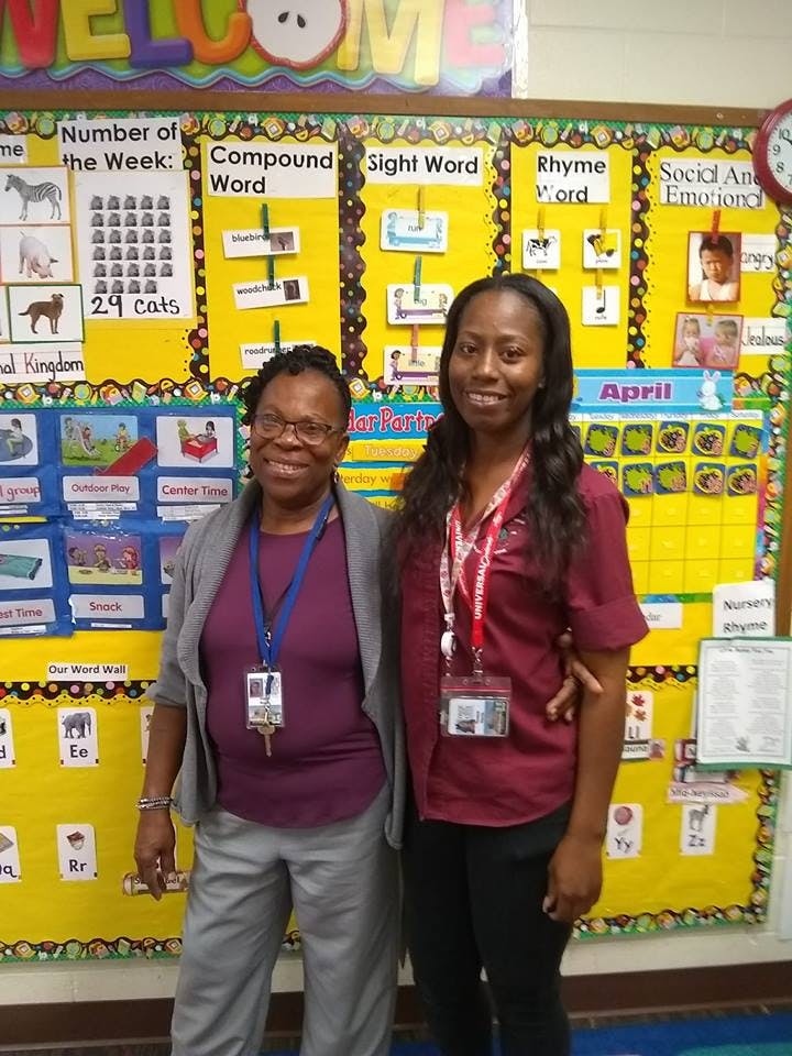 Two people standing in front of a classroom bulletin board