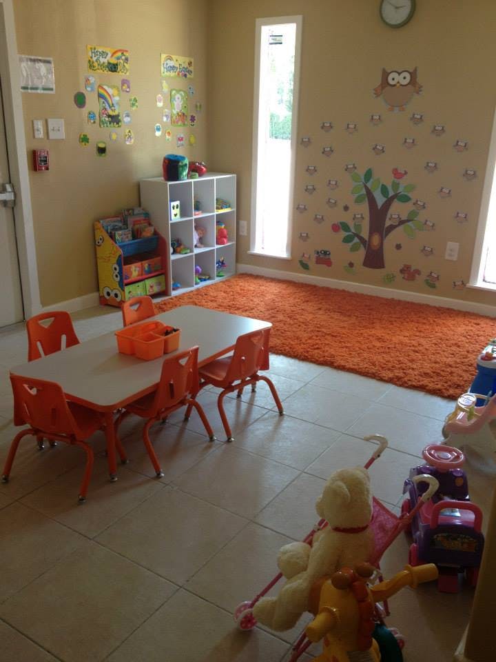 Children's play area with small table and chairs, shelves, and an orange rug