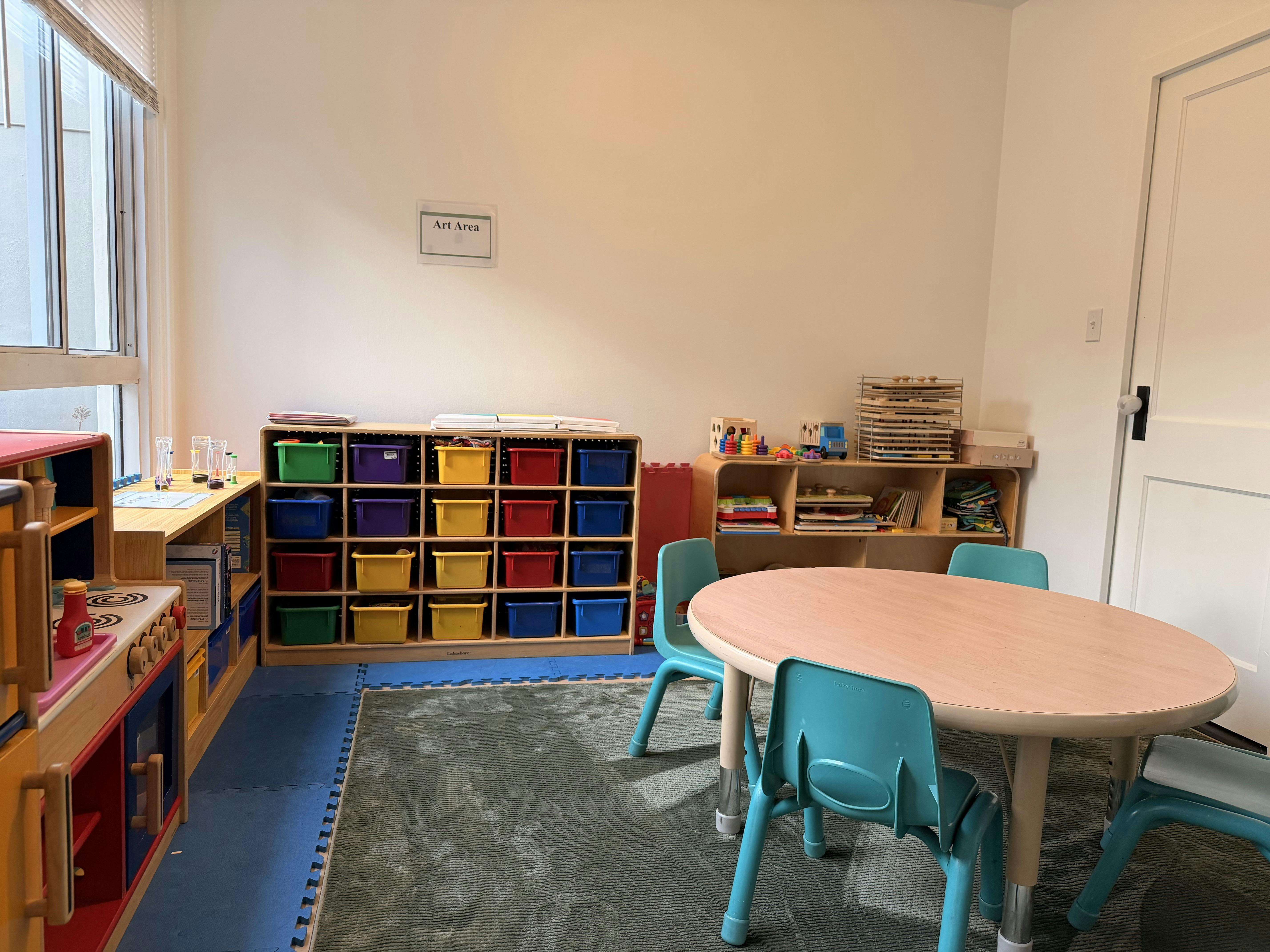 Classroom with colorful storage bins, small table, and chairs