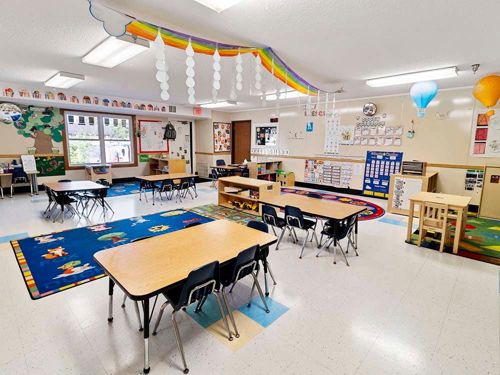 Empty colorful preschool classroom with small tables and chairs