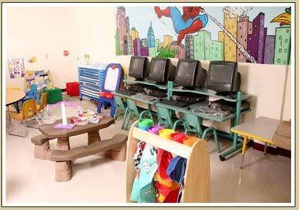 Classroom with computers, a small picnic table, and a dress-up rack
