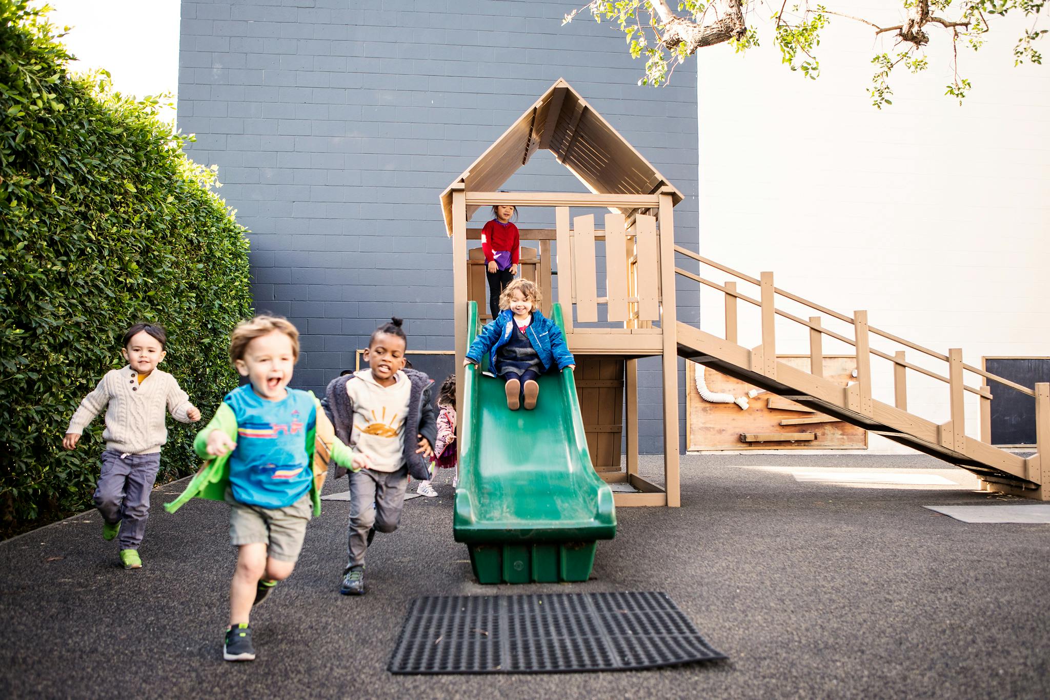 Children playing on a playground with a slide and climbing structure