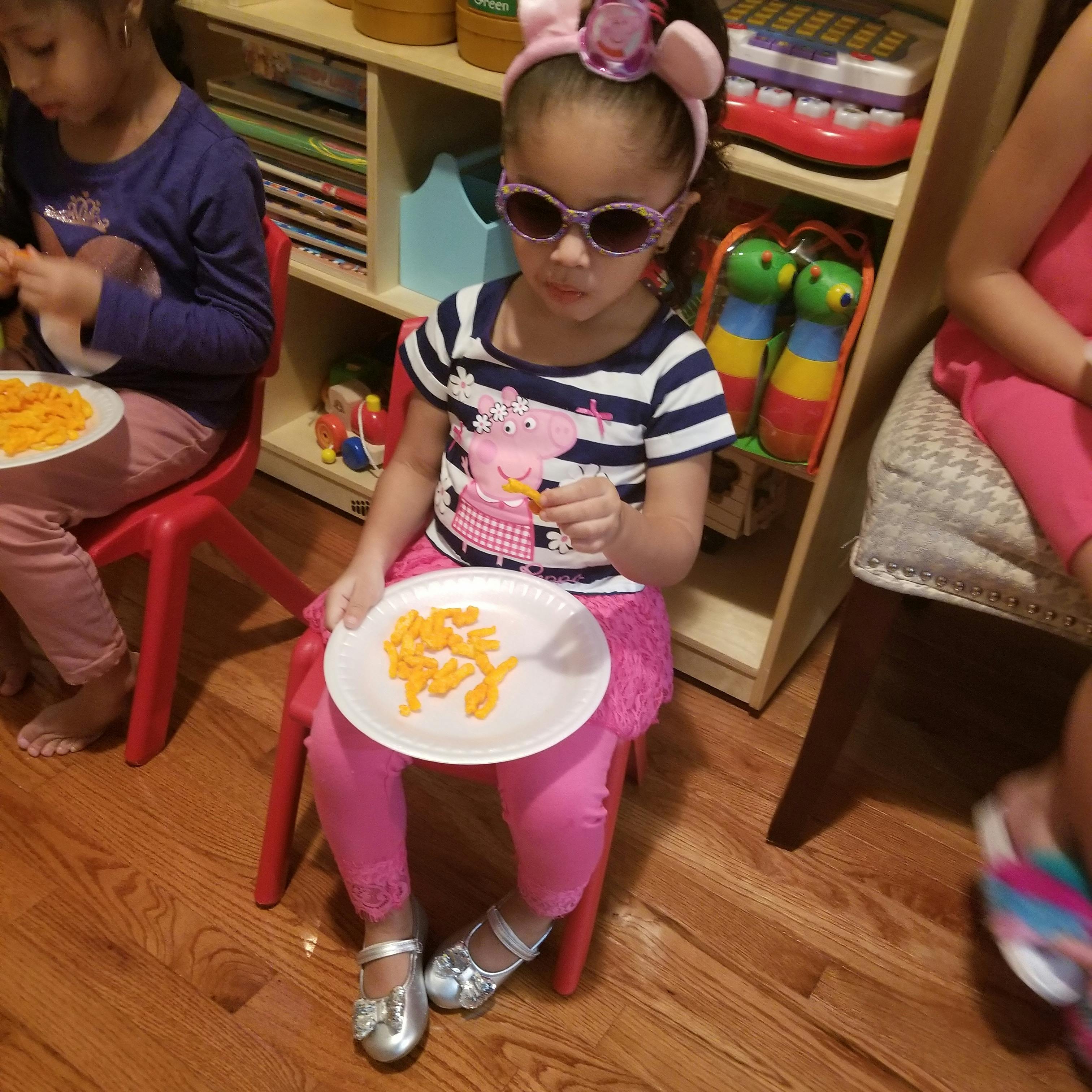 Child in sunglasses holding a plate of snacks