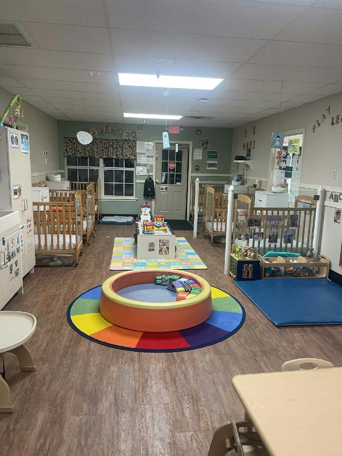 cribs in a baby playroom with a colorful play mat and ball pit