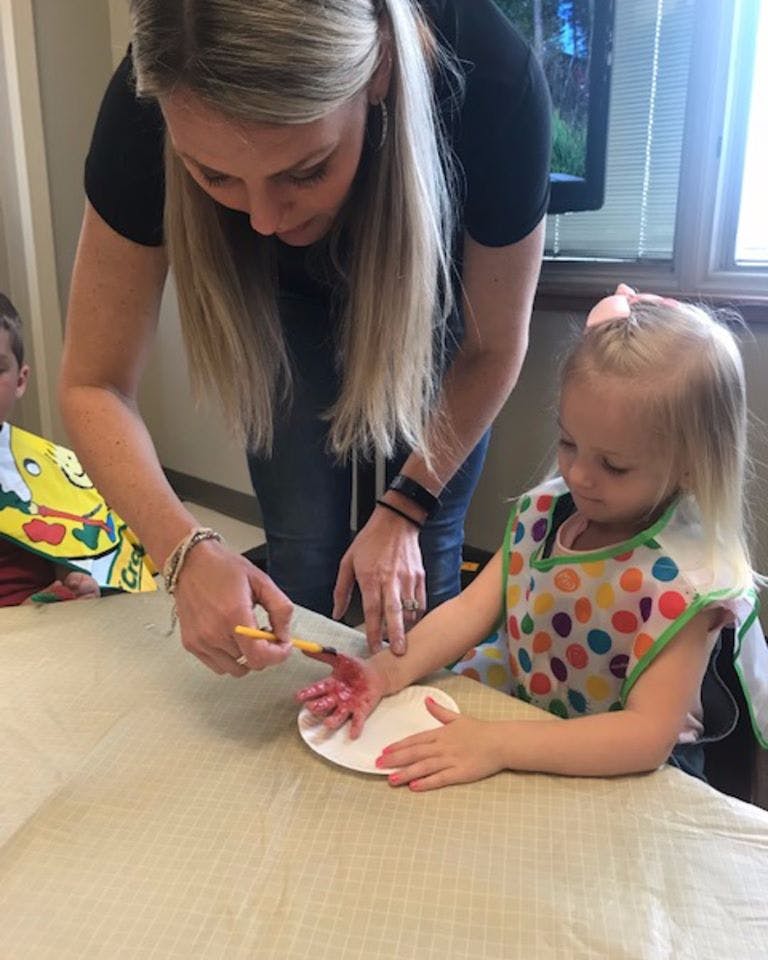 Person helping a child paint their hand