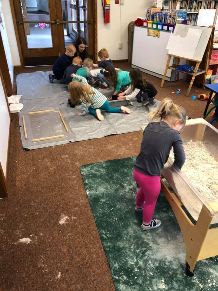 Children playing with sand and other materials in a classroom