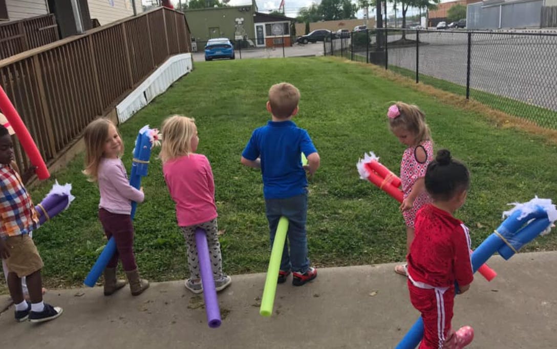 Children playing with pool noodles outdoors