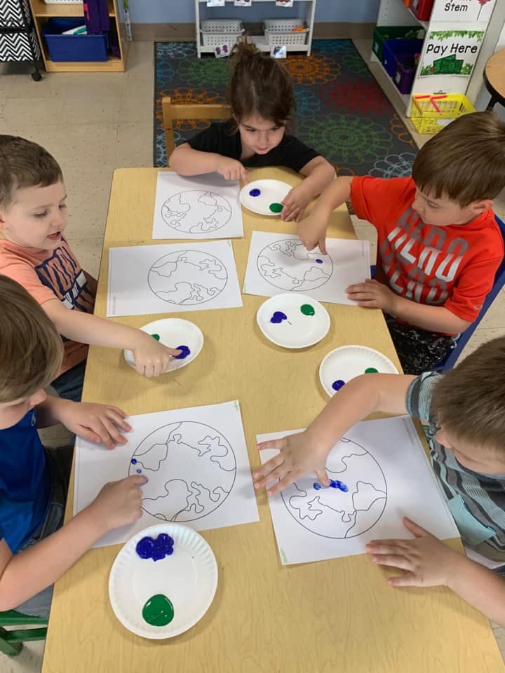 Children finger painting outlines of the Earth
