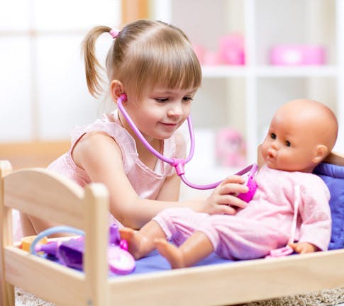 Child playing doctor with a doll and toy stethoscope