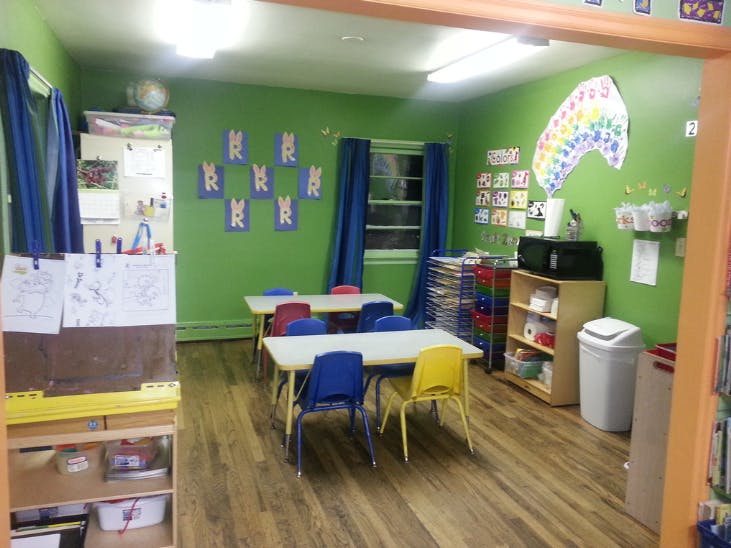 Classroom with green walls, small tables, and colorful chairs