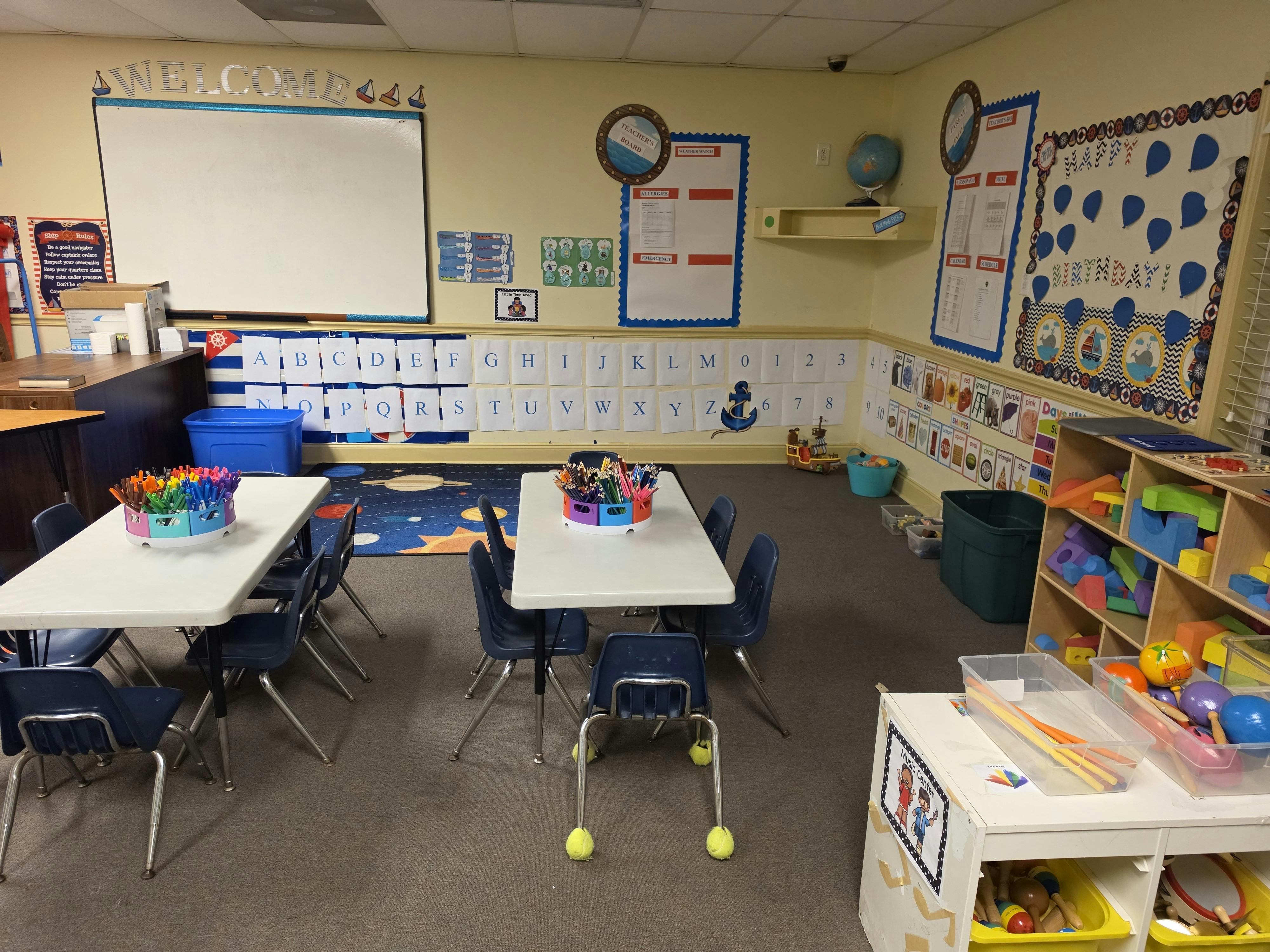 Classroom with small tables and chairs, whiteboards, and educational posters