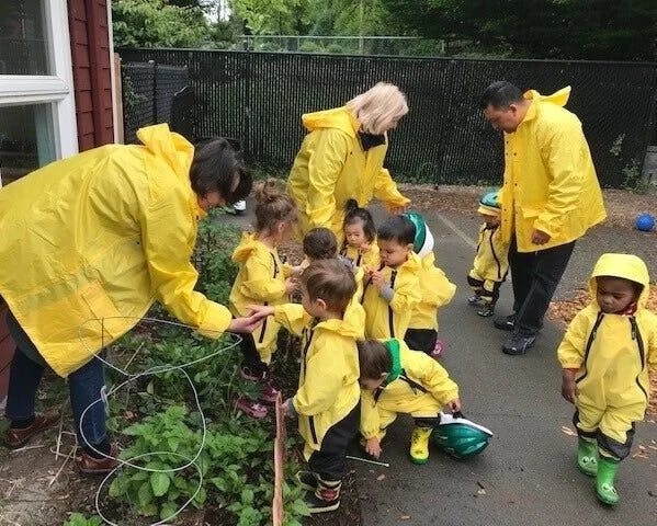 People and young children in yellow rain gear in a garden