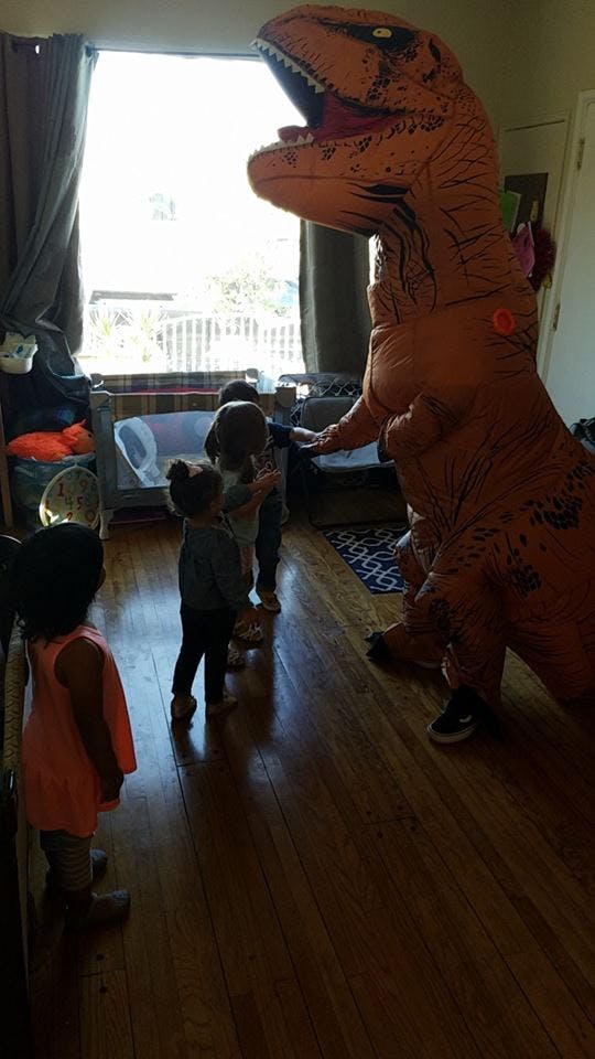 Person in dinosaur costume interacting with children