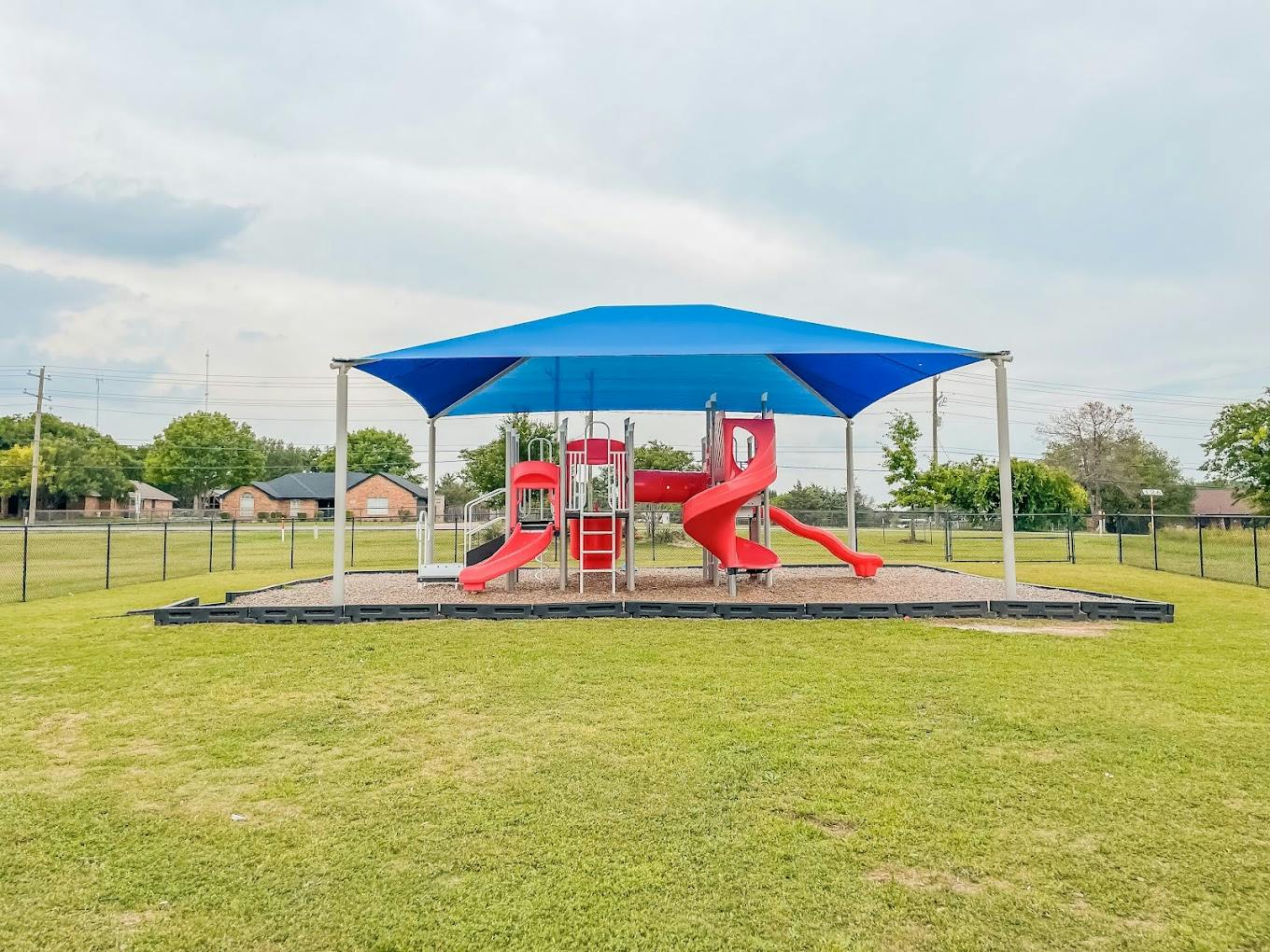Playground structure with slides under a large blue shade canopy