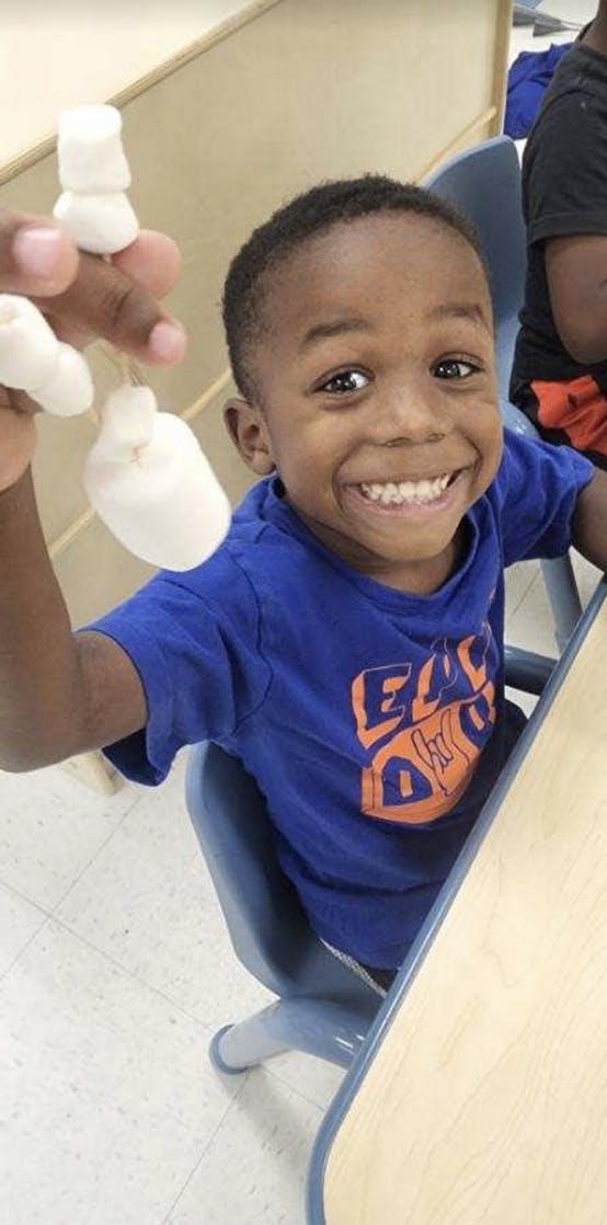 Child holding marshmallows on a string