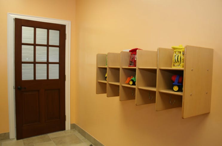 Brown door with glass panes next to wall shelves with toys