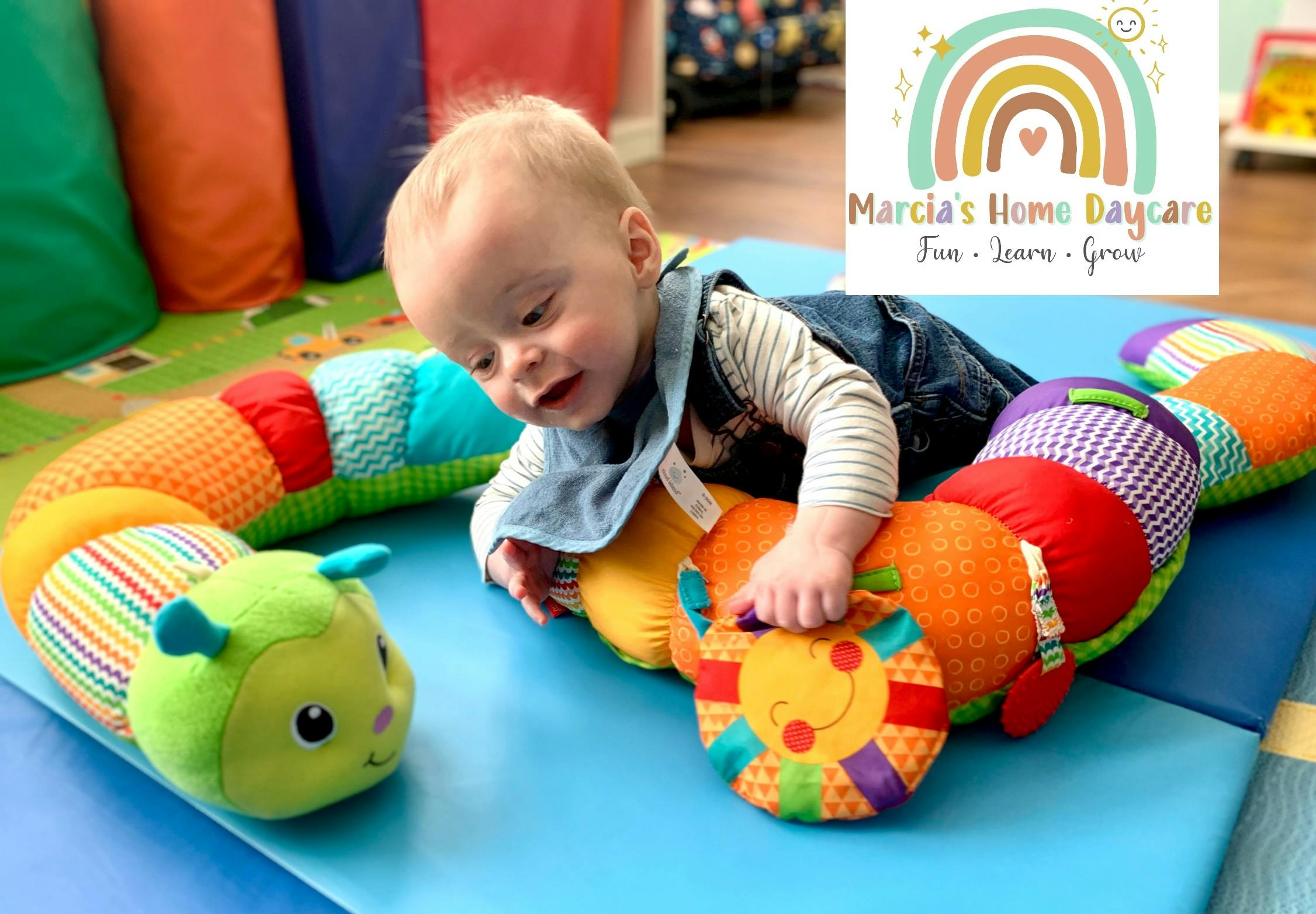 Child playing with a colorful caterpillar toy on a blue mat