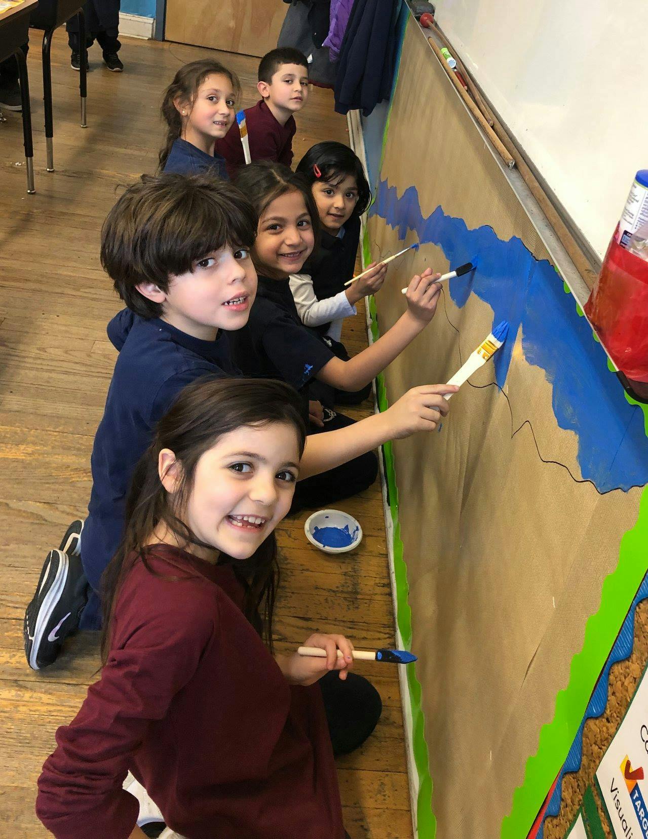 Children painting a mural in a classroom