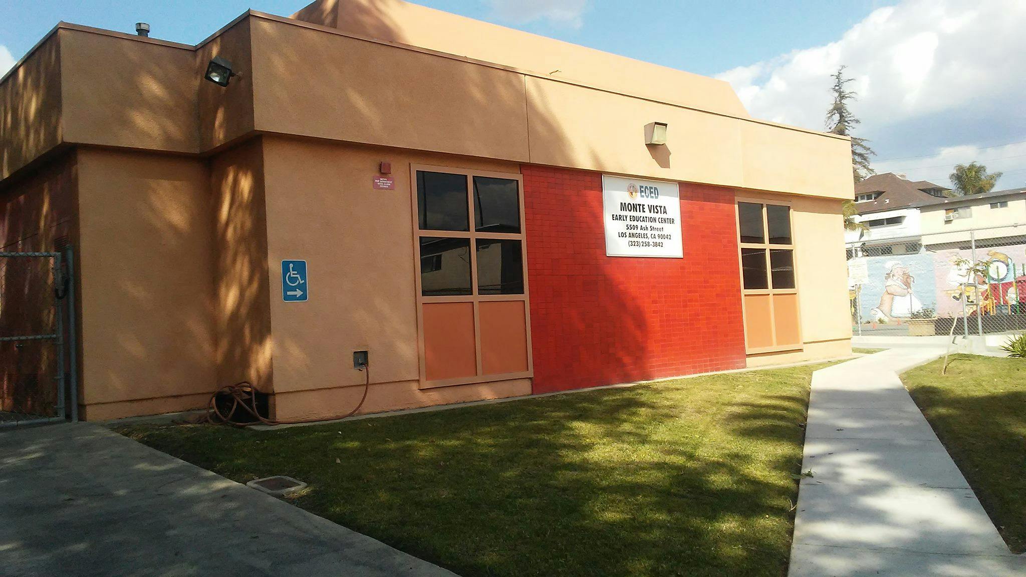 Building exterior with red and tan walls, windows, and a sidewalk