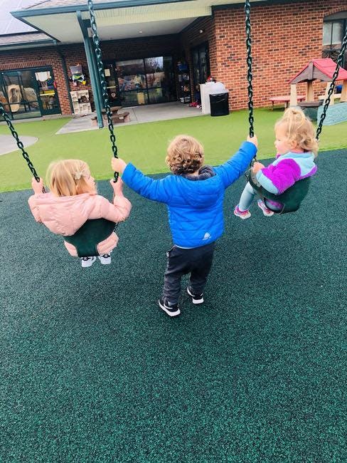Three children on swings in a playground
