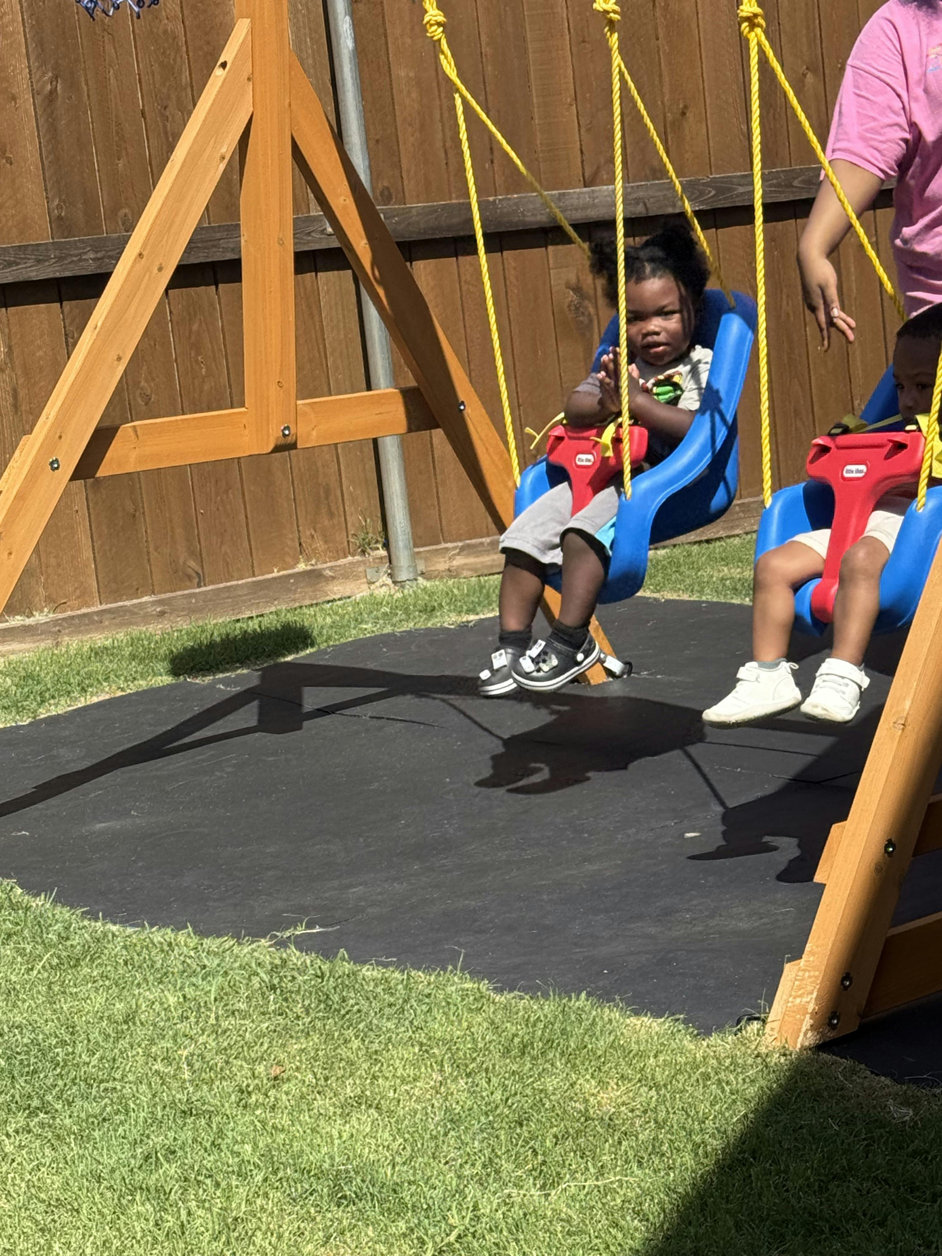Two children sitting on backyard bucket swings