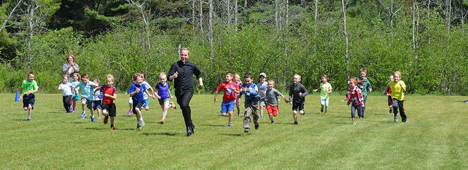 Adult and children running on a grassy field