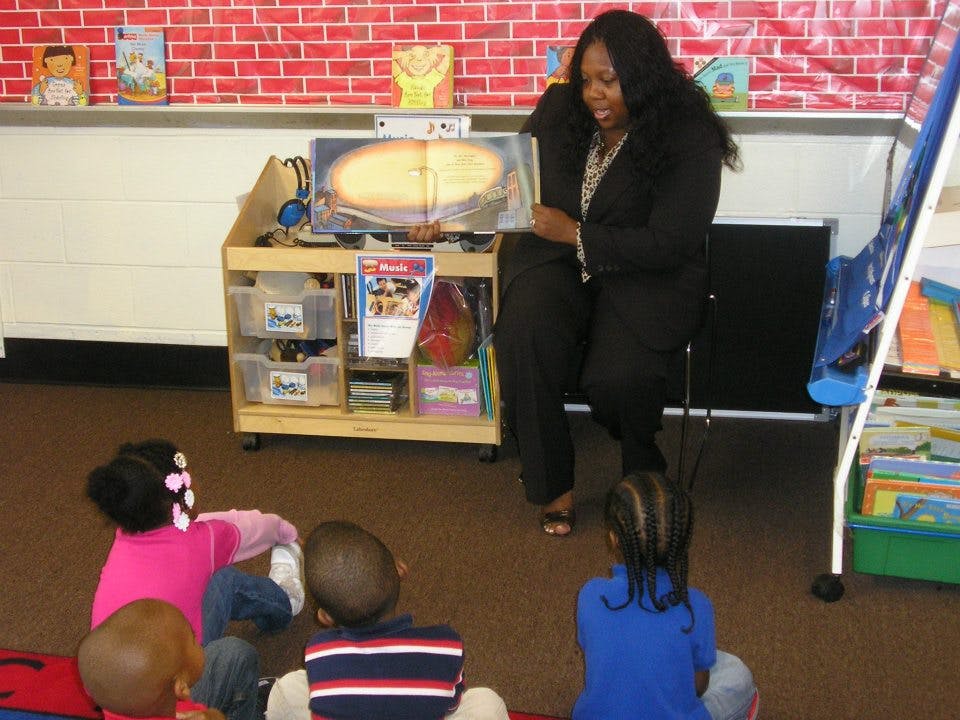 Person reading a book to children in a classroom