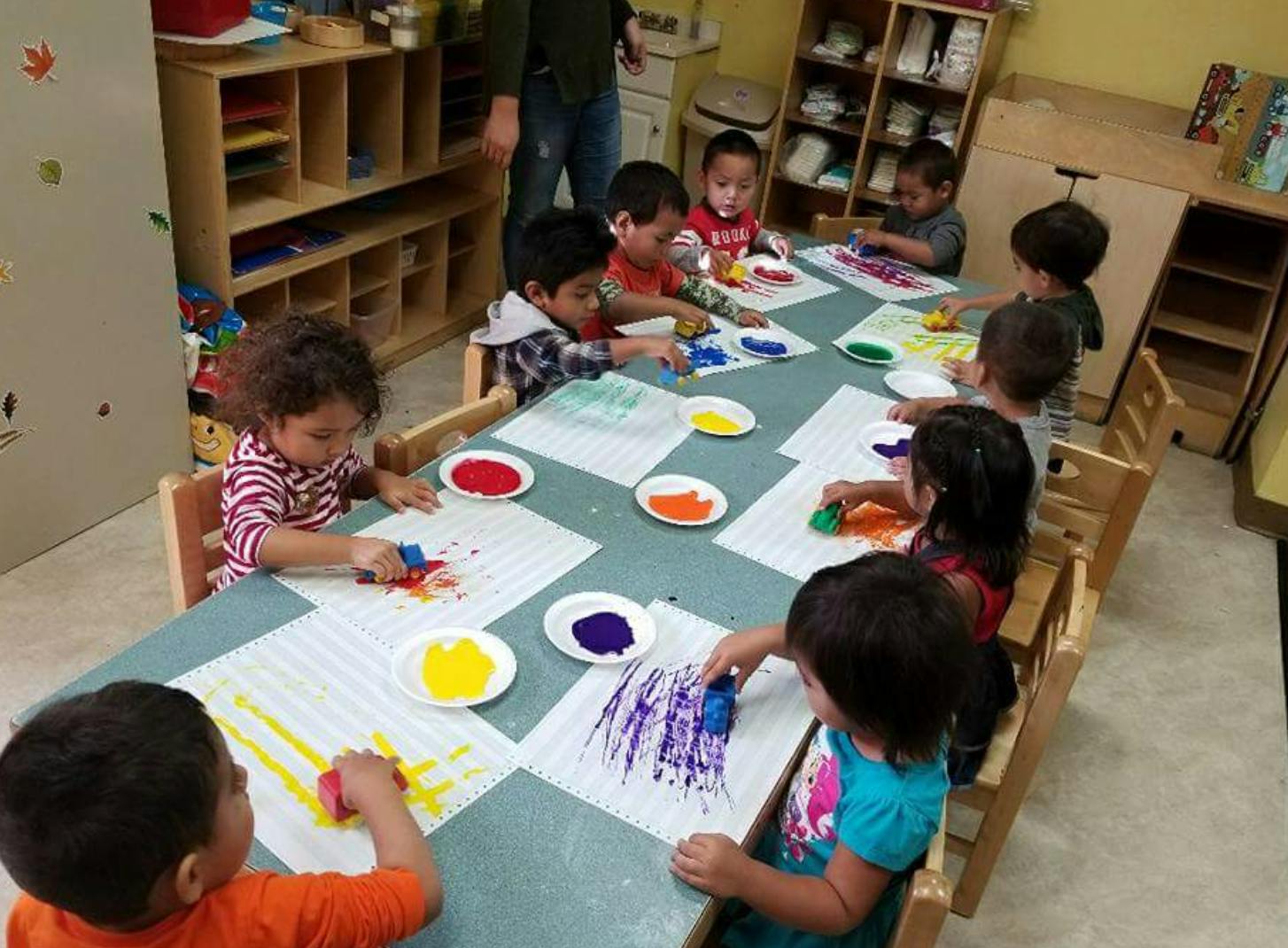 Children painting at a table in a classroom