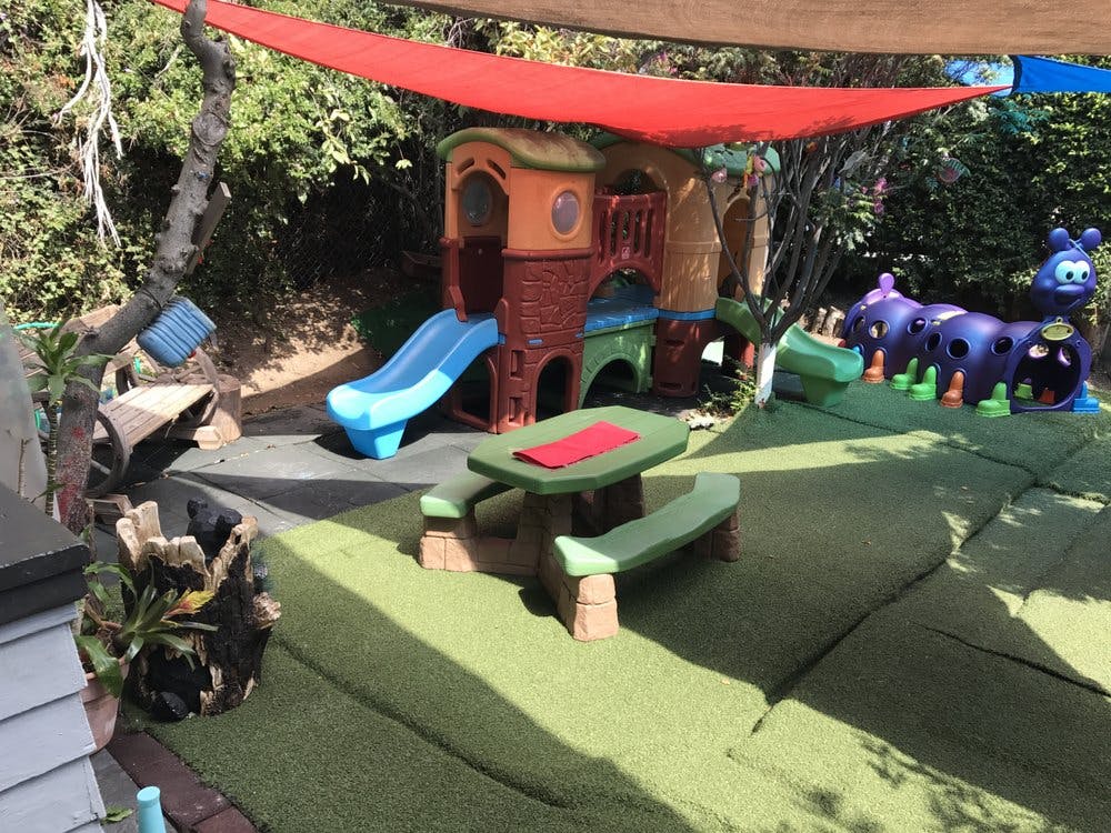 Outdoor playground with playhouse, slide, picnic table, and caterpillar toy