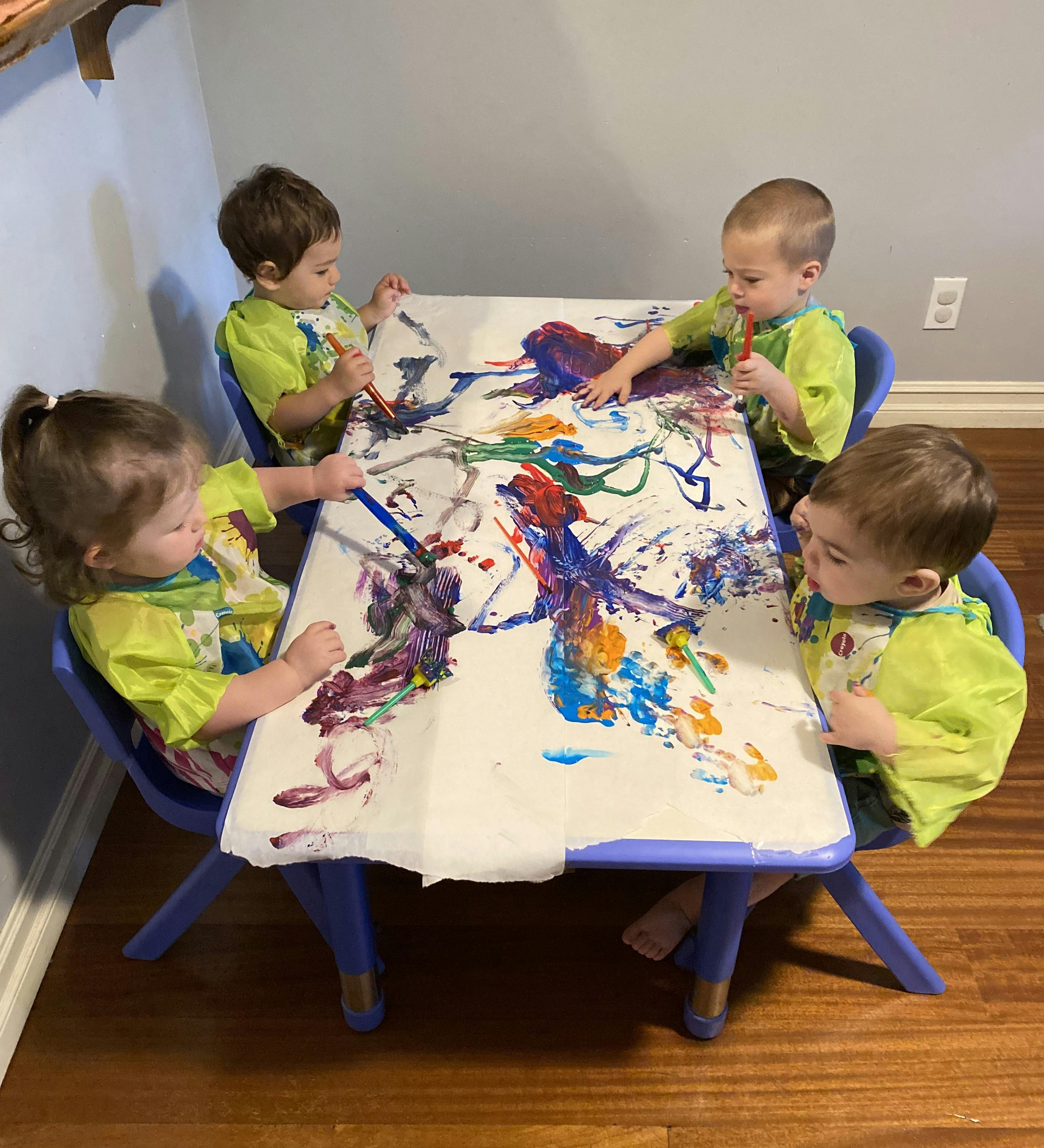Four children painting at a table
