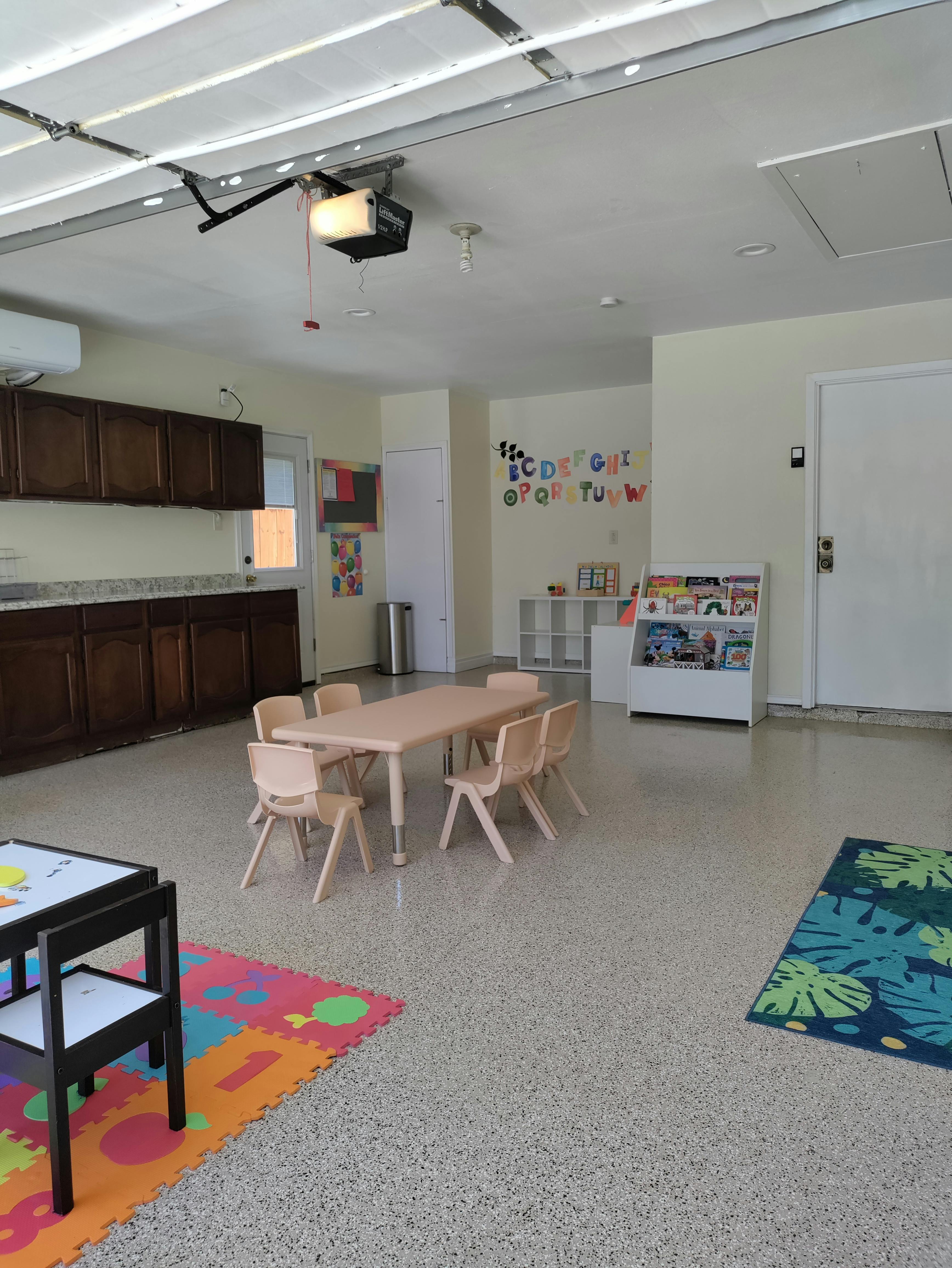 Classroom with small table and chairs, kitchen cabinets, and alphabet on wall