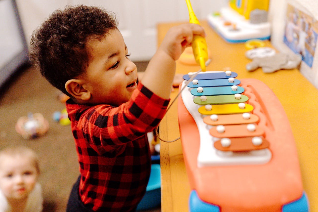 Child playing a toy xylophone with a mallet