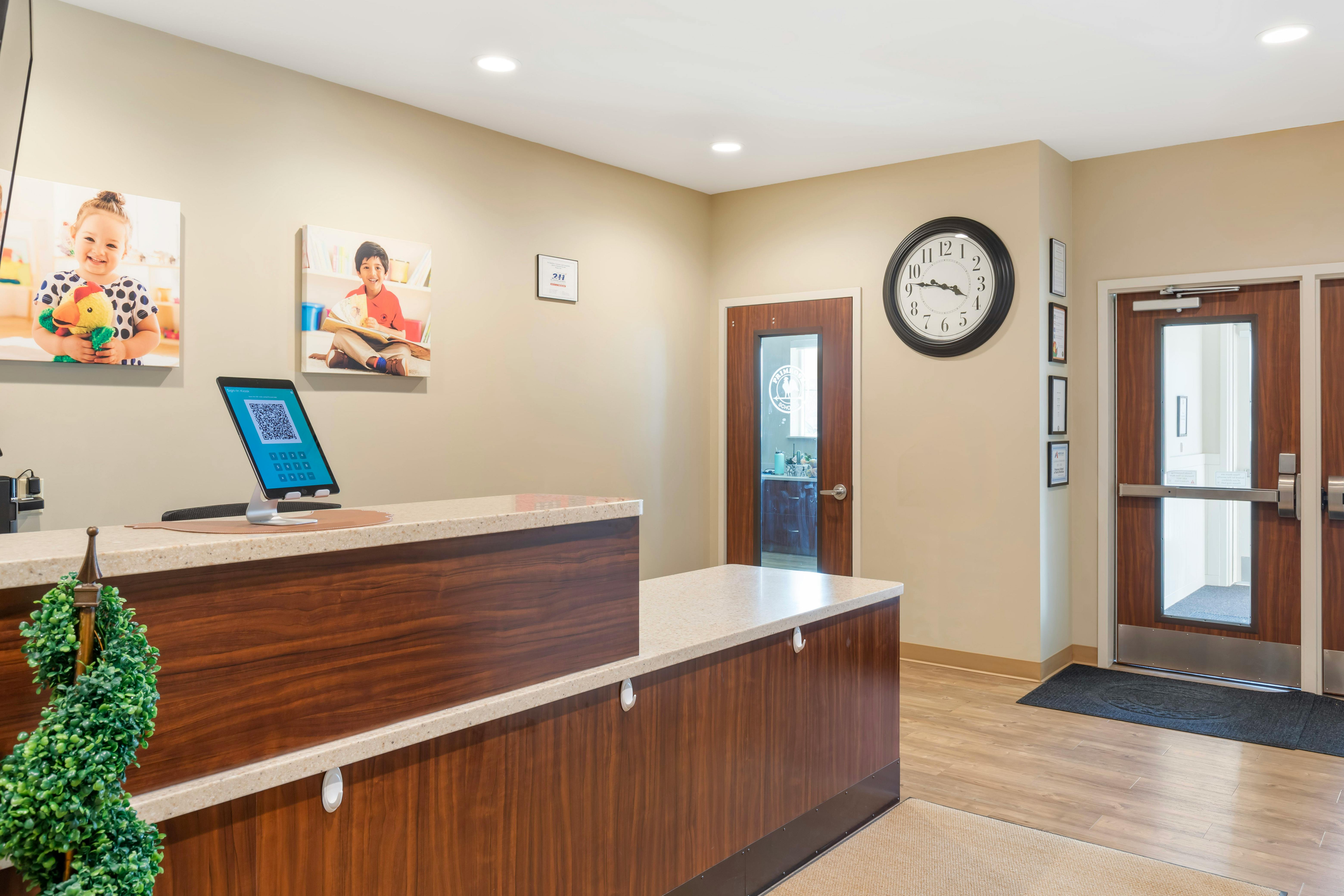 Reception desk with a tablet displaying a QR code, a clock, and two doors