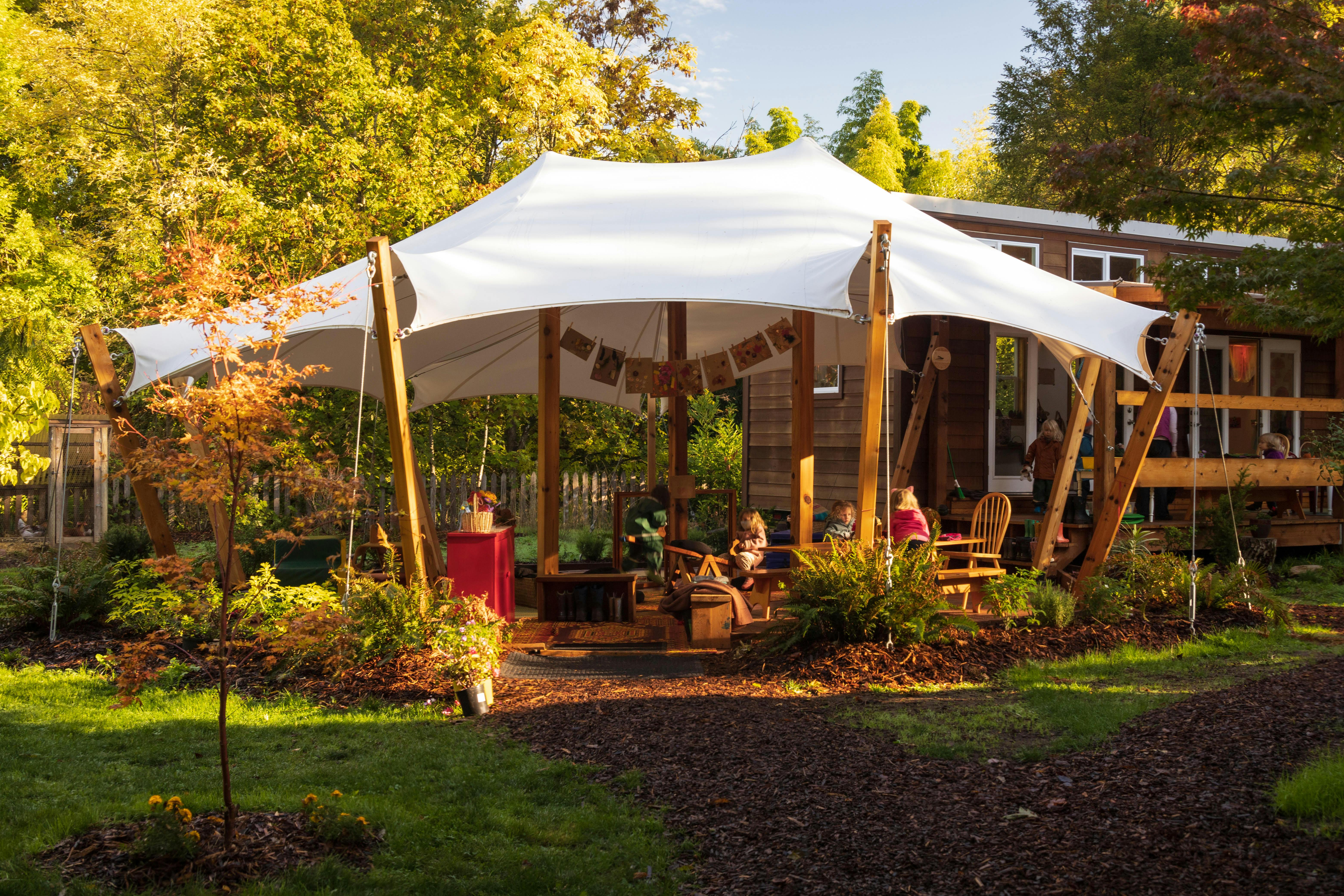 White tent structure with wooden poles in a garden setting