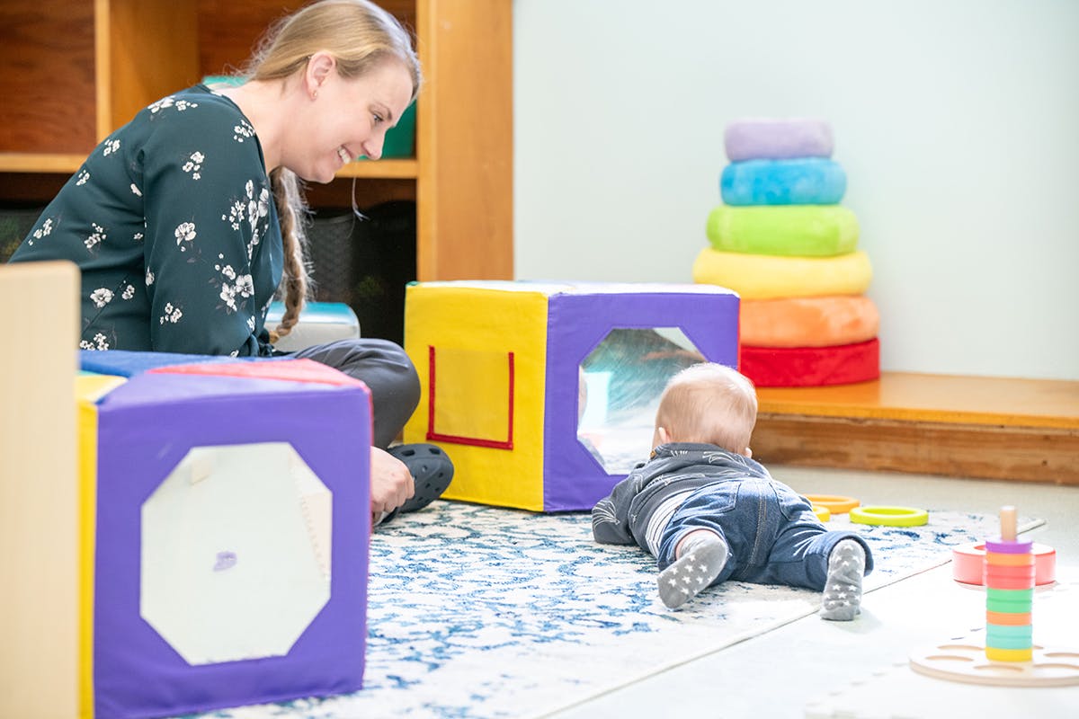 Person and child playing with soft blocks on a rug