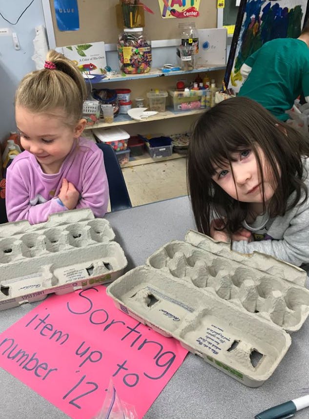 Two children with egg cartons and a sign that says "Sorting item up to number 12"