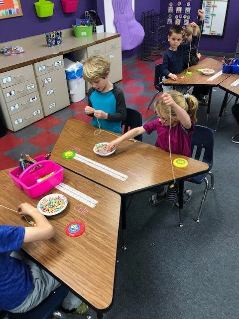 Children stringing beads in a classroom